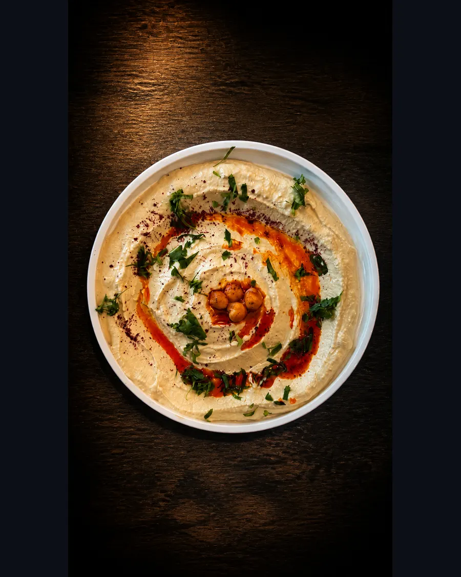 Hummus garnished with chickpeas, herbs and spiced oil